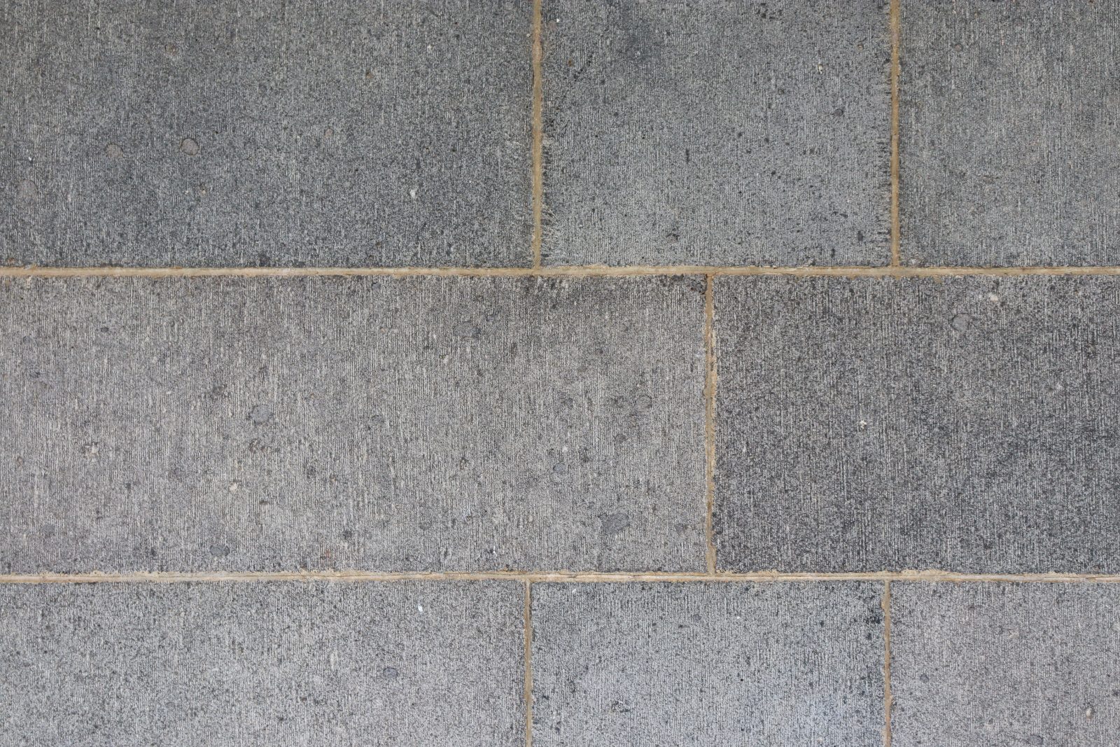 Gray concrete tiles arranged in a grid pattern with tan grout lines